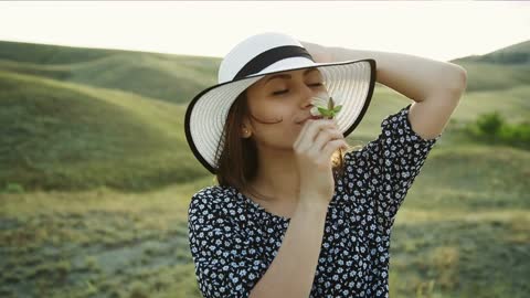 Woman in the countryside smelling a white flower