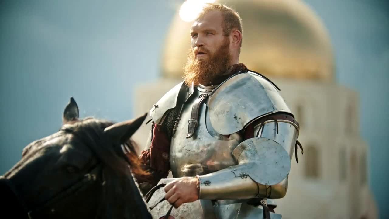 A bearded man knight riding a horse on the field - medieval festival