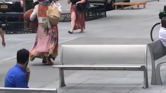 Security following colorful homeless person floral feathers