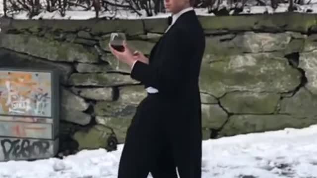 Guy Slides Down Icy Road While Wearing Suit and Holding Wine Glass in his Hand