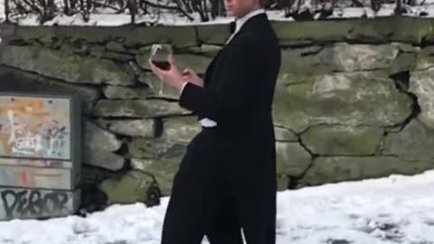 Guy Slides Down Icy Road While Wearing Suit and Holding Wine Glass in his Hand