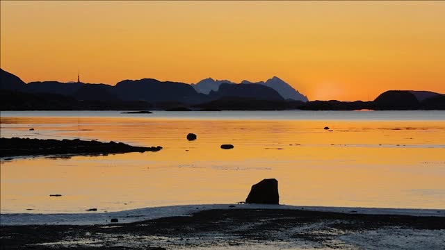 timelapse of tide and sunset over mountain in a fjord