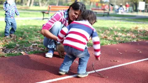 Young mother playing with her son and puppy in autumn park, steadycam