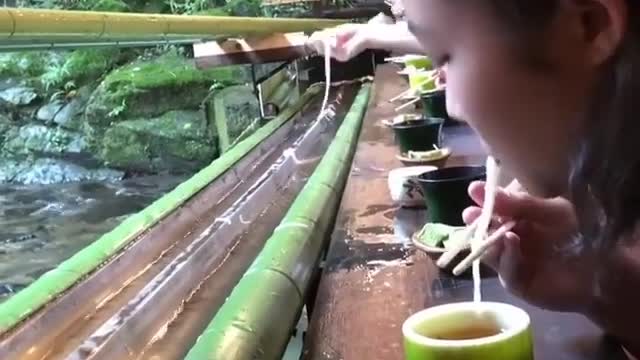 Would you eat noodles falling from a bamboo slide while sitting in front of a waterfall?🤔