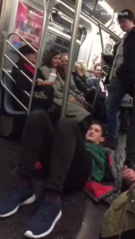 Man laying on floor pretending to walk on subway pole
