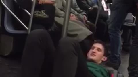 Man laying on floor pretending to walk on subway pole