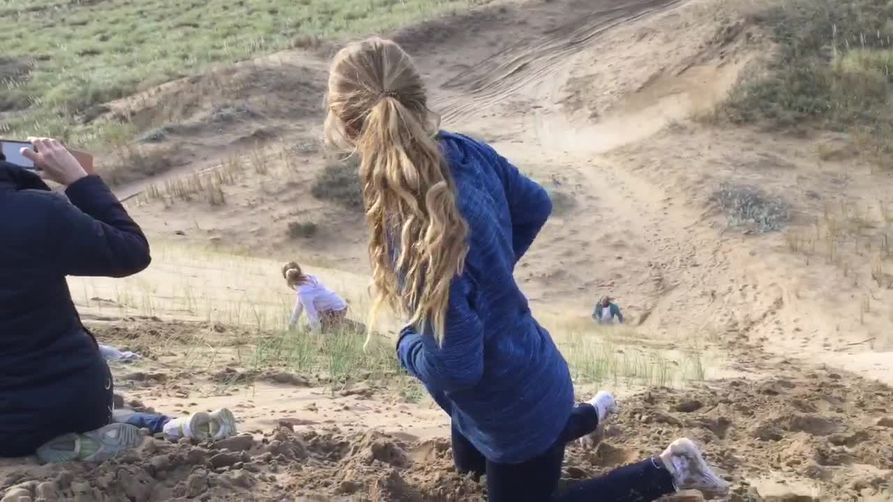 White shirt boogy boards down sand dune backwards and gets whiplash