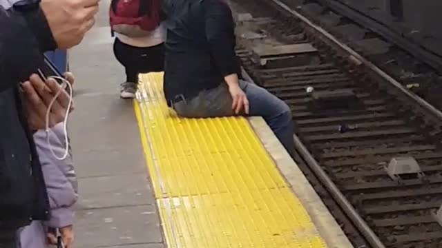 Couple hang feet off subway terminal and get up awkwardly