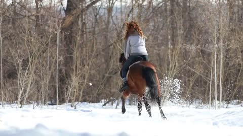 A woman running on a horse in the forest on a snowy ground