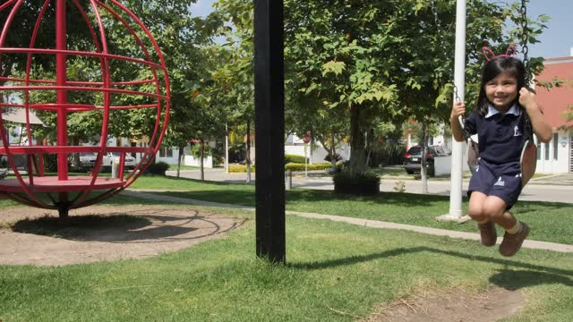 Happy little girl on a swing in a park