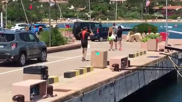 Man in orange and black carries small weights on dock