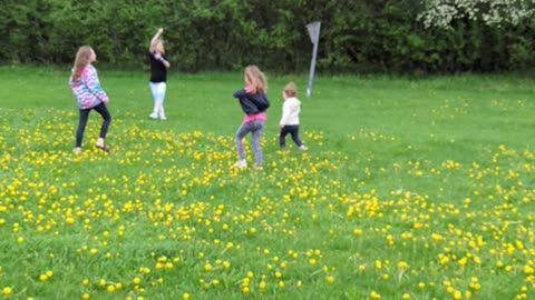 Girls watching a friend fly a kite.