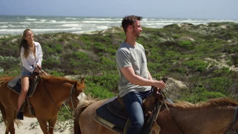 Smiling Couple Rides Horses on Beach