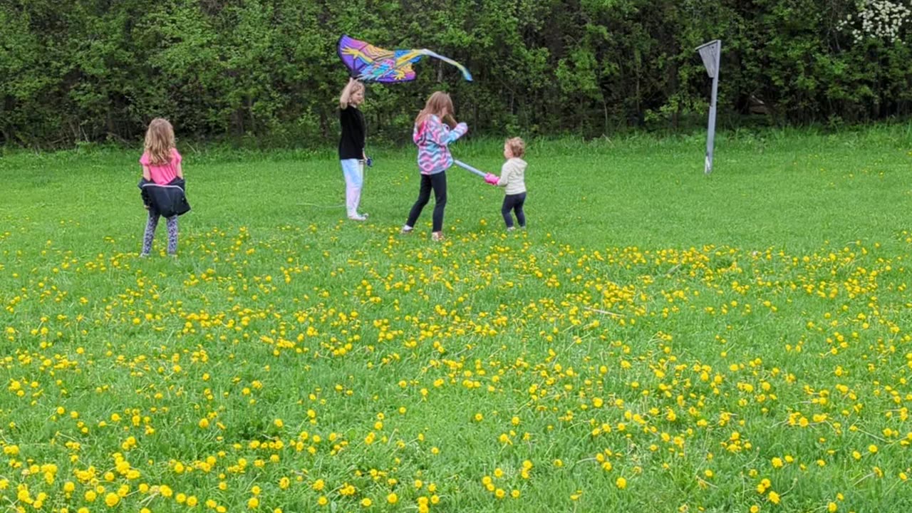 Girls with a friend flying a kite.