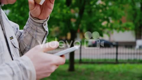 A Man Walks With The Phone And Coffee Cup In The Frame Only Hands Seen