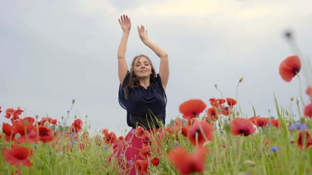 Dancing happily in the middle of a field of pink and blue flowers, during a bright day.