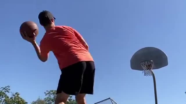 Guy Dribbles Two Basketballs and Throws Them in Basket While Balancing over Slackline