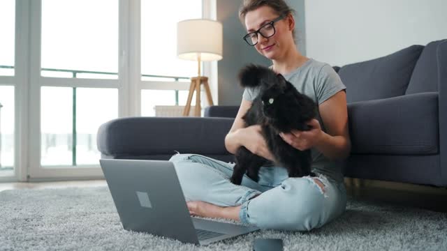 Casually dressed woman sits on a carpet with a laptop