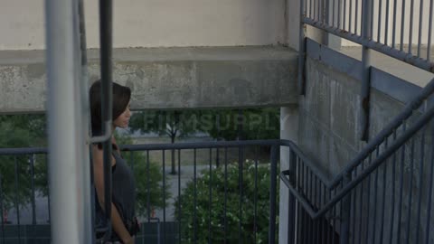 A brunette woman walking up a flight of outside stairs