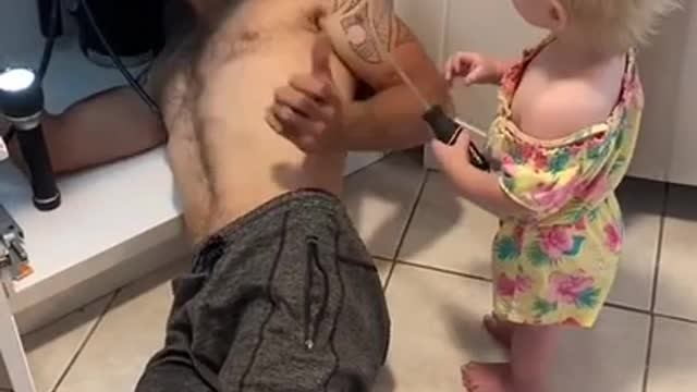 Toddler Holds Screwdriver Up At Dad While He Fixes Sink in Kitchen