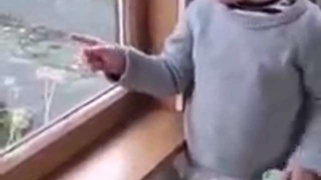 Funny baby showing her mum a goat outside