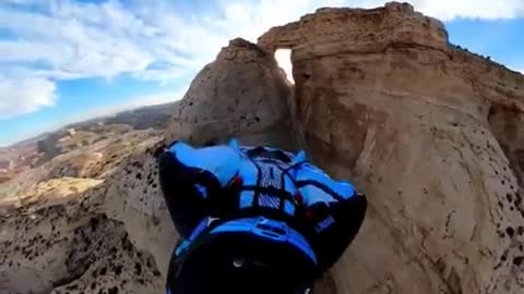 Wingsuit through a hole in the rock