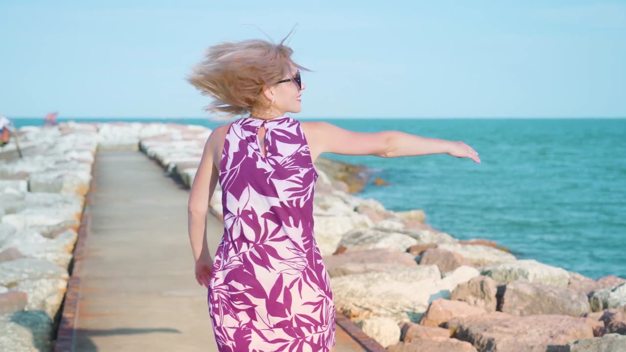 Young blonde girl spinning by the sea