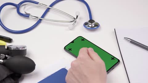 Over the Shoulder Shot of Medical Professional Using Smartphone Touchscreen with Green Screen