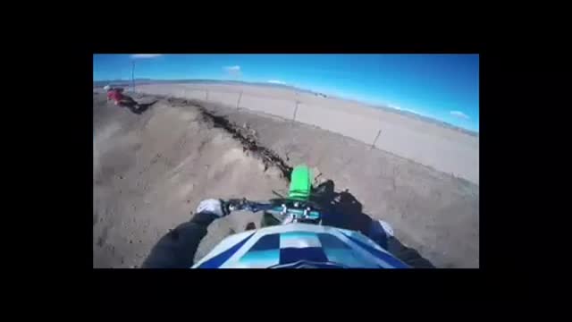 Green motorcycle jumps dirt ramp falls into wire fence