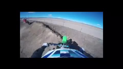 Green motorcycle jumps dirt ramp falls into wire fence