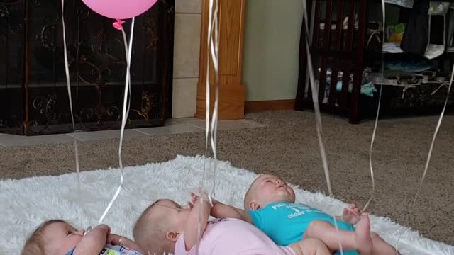 Triplets Playing with Balloons