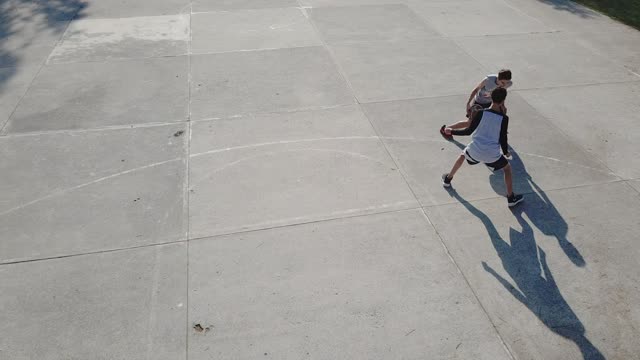 Two boys playing basketball outdoors