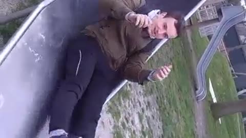 Green jacket slides down tube and falls down in playground