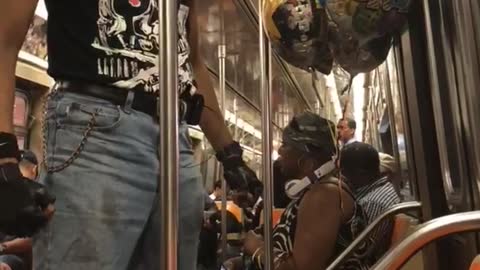 Guy dancing fighting moves subway door blue hat black shirt
