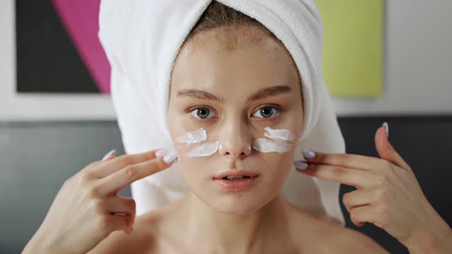A Woman Applying Facial Cream On Her Face
