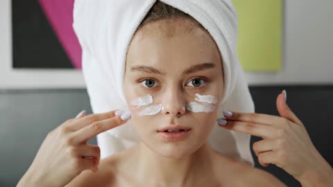 A Woman Applying Facial Cream On Her Face