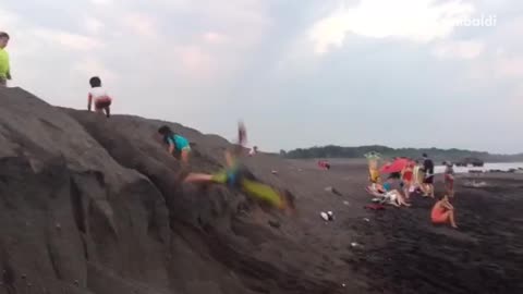 Boy in green water suit faceplant in sand