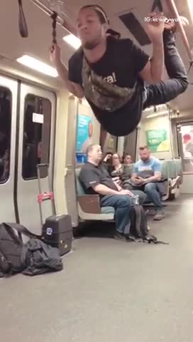 A man hangs from train had rails and performs