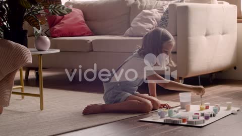 Blonde Girl Sitting On The Floor And Painting Animal Pieces In Living Room 4