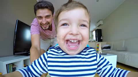 Happy dad pushing his son in the walker across the house أب سعيد يدفع ابنه في المشاية عبر المنزل