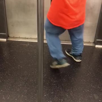 Guy orange staff shirt running dancing spinning around pole subway