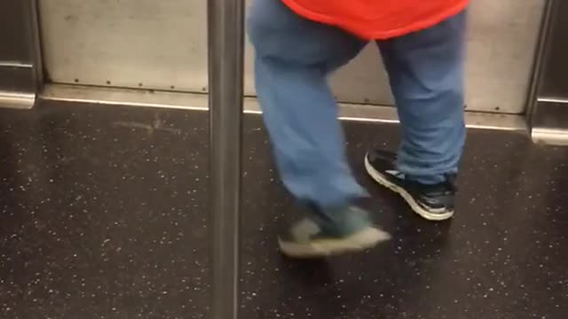 Guy orange staff shirt running dancing spinning around pole subway