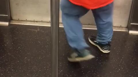 Guy orange staff shirt running dancing spinning around pole subway