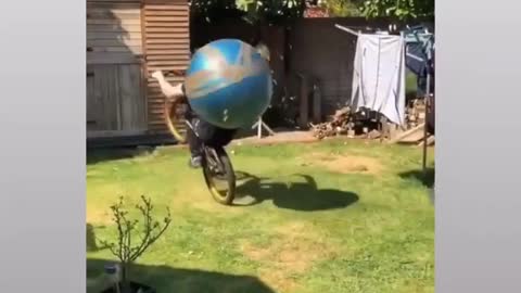 Man on bicycle somersaulting with ball