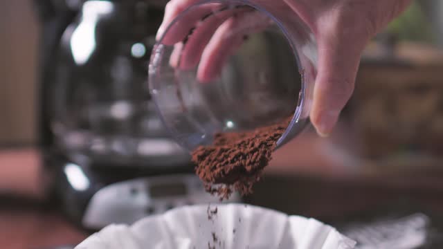 Coffee powder being poured on the coffee maker filter