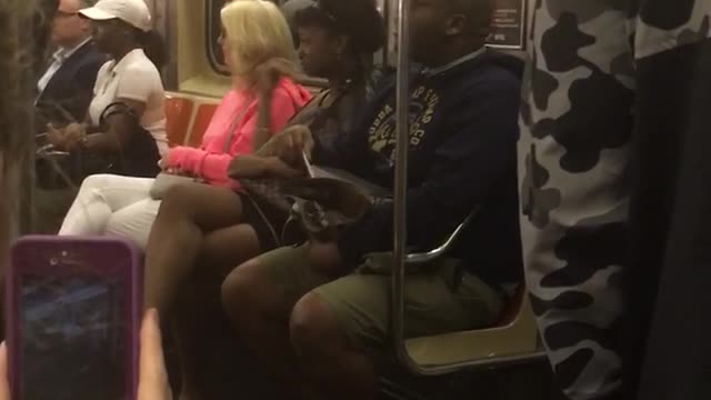 A man in a blue sweater singing on subway train