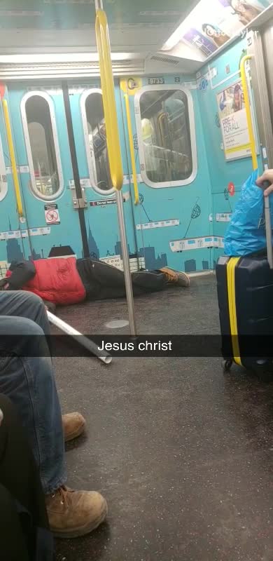 Man sleeping on floor in subway holds long white tube against his mouth