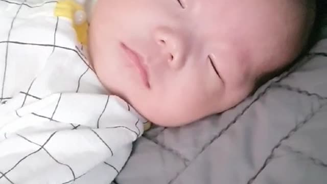 As the baby sleeps, he opens his eyes slightly