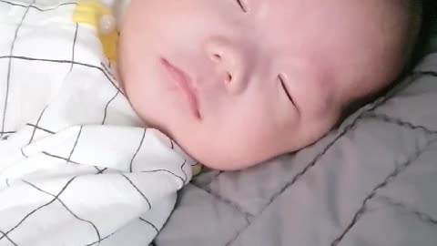 As the baby sleeps, he opens his eyes slightly