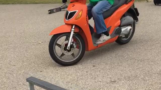 Guy in green rides orange bike into fence